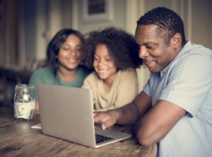 A "cents-able kid" raising family sitting at a table, just you, looking at a laptop.