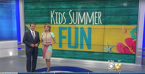 Two people standing in front of a tv screen that says kids summer fun.