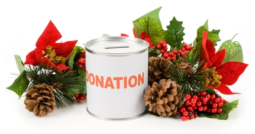 A donation tin with holly and pine cones, encouraging people to donate to teach kids.