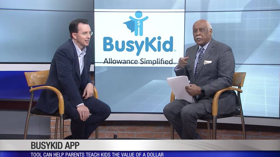 Two men sitting in front of a busykid-branded tv.