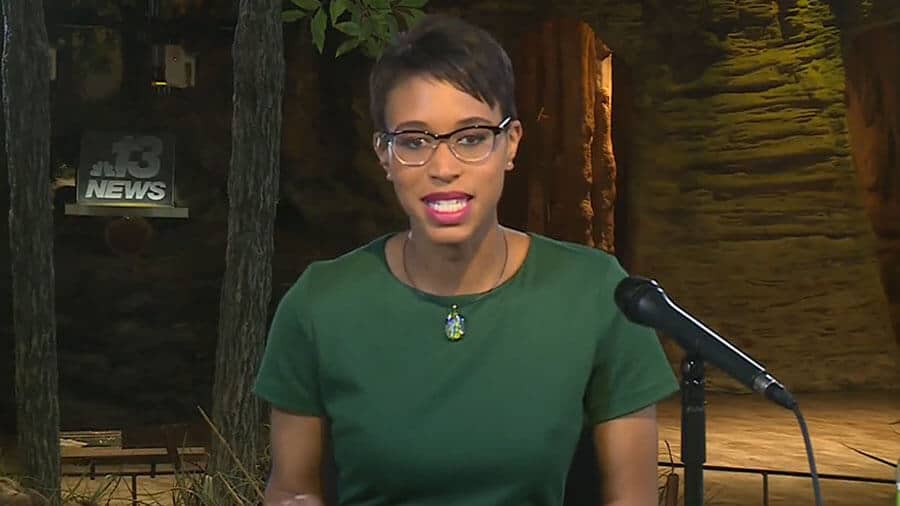 A woman in glasses is speaking into a microphone at HNN.